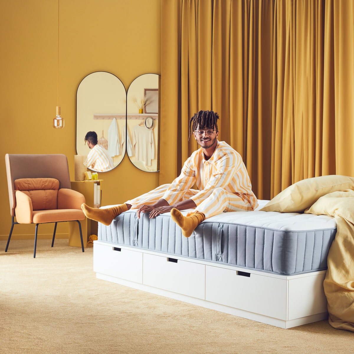 a man is sitting on a mattress and smiling