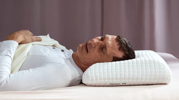 A man sleeping on a high pillow on his back.
