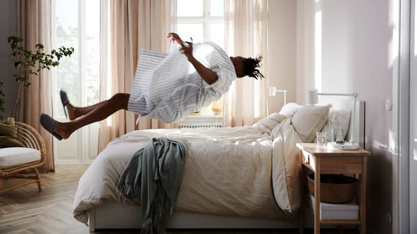 A man throws himself backwards to land on top of a MALM bed with a VATNESTRÖM pocket sprung mattress.