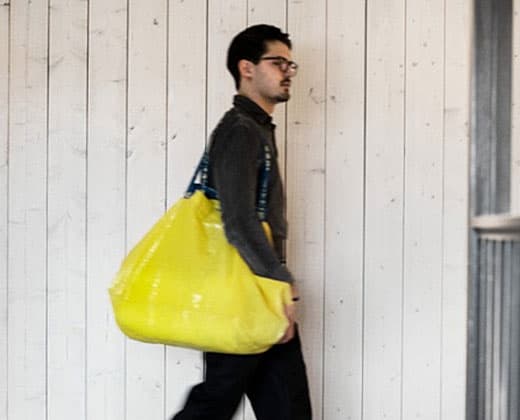 A man walking with a yellow IKEA bag.
