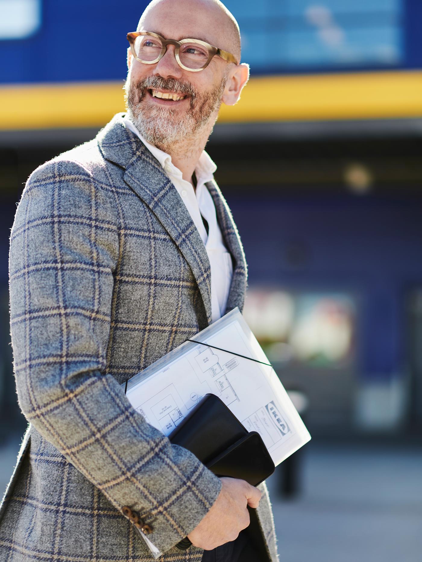 A man with a beard and glasses carrying a folder containing IKEA documents.