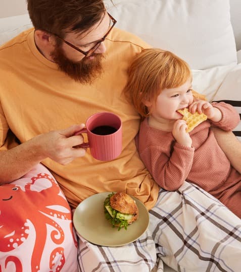 A man with a kid in PJ having breakfast 