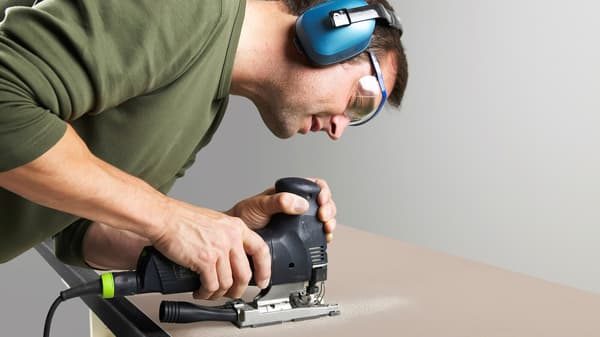 A man working on a kitchen countertop with a tool