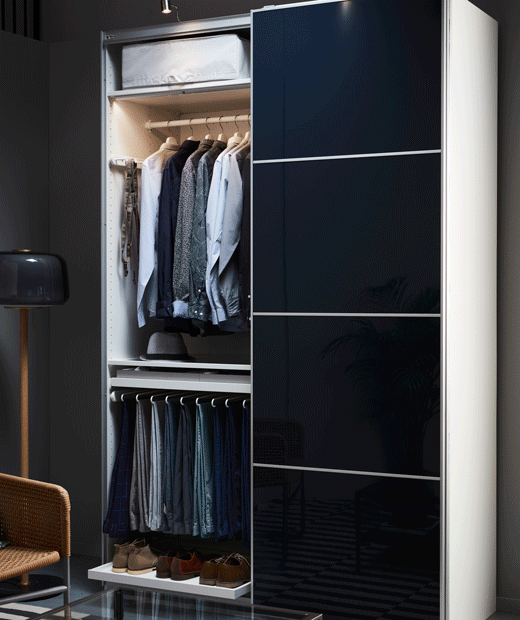 A man’s closet with high-gloss black-blue IKEA HOKKSUND panels for sliding door frames.