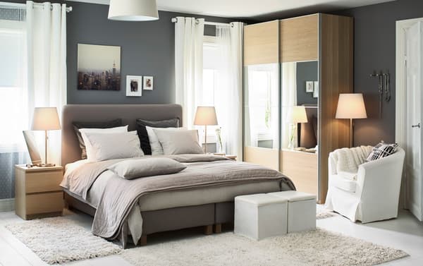 A medium bedroom with IKEA LAUVIK dark beige divan bed and two wood coloured chest of drawers used as bedside tables.