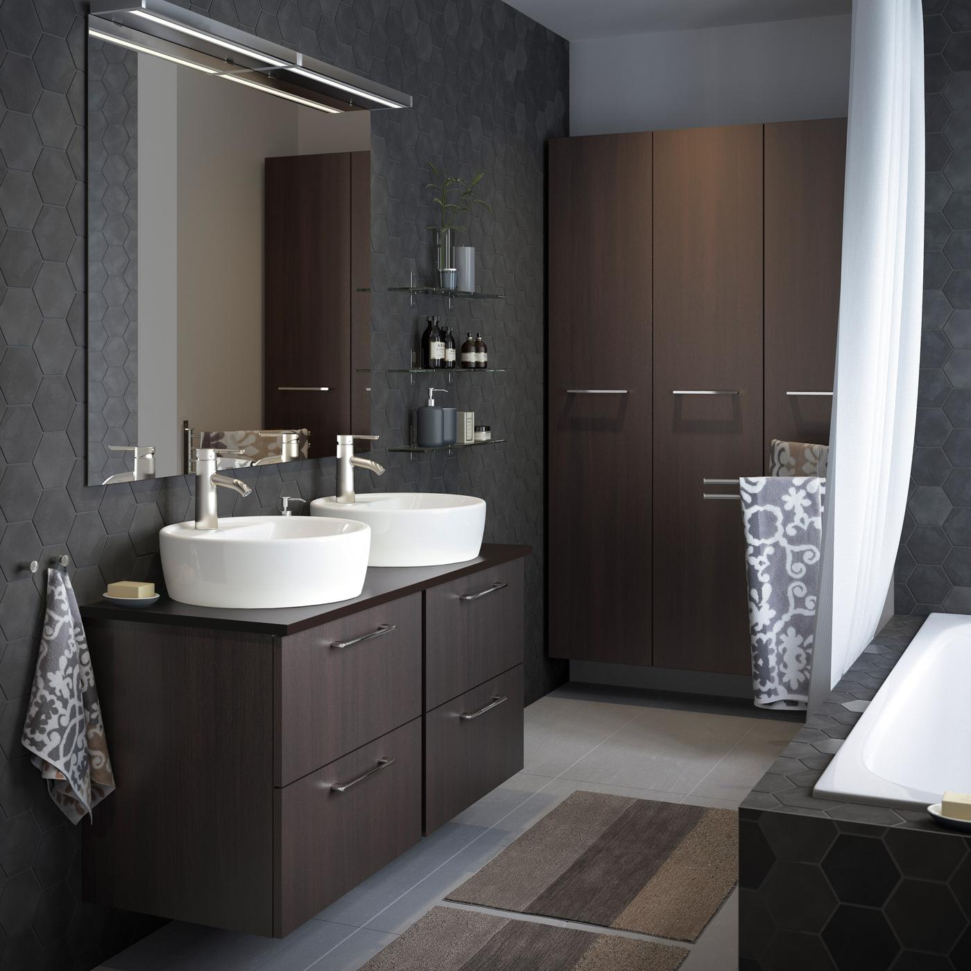 A medium size grey bathroom with high and low wall cabinets in black-brown with chrome-plated handles.