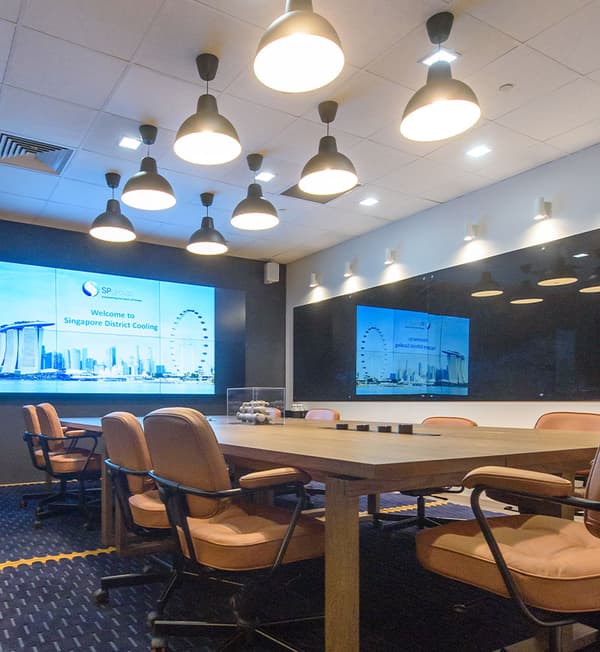 A meeting area featuring black ceiling lights shining on a long wooden table.