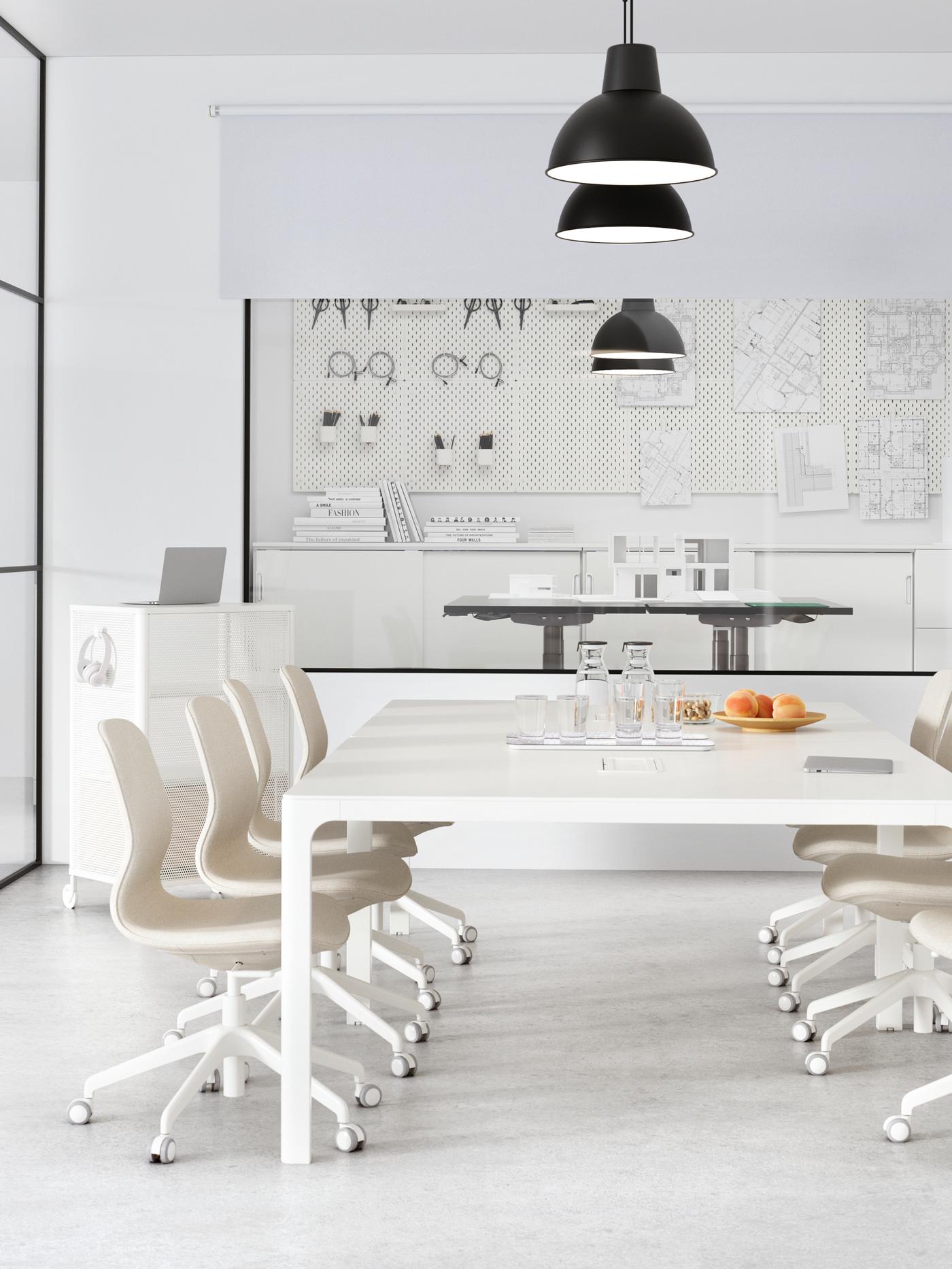 A meeting room with a white wall, two large white tables and several beige LÅNGFJÄLL conference chairs.
