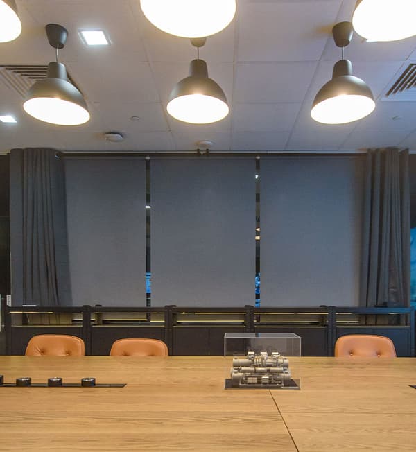 A meeting room with grey curtains behind that are open.