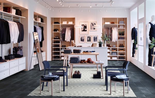 A men’s clothing store with four IKEA ELVARLI storage units around the room, with two LISABO light wood tables in the centre.