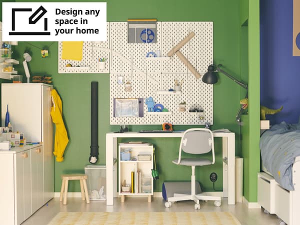 A mid shot of a children's room with a white PÅHL desk, white SKÅDIS pegboard wall solution and white SMÅSTAD / PLATSA storage solution. 