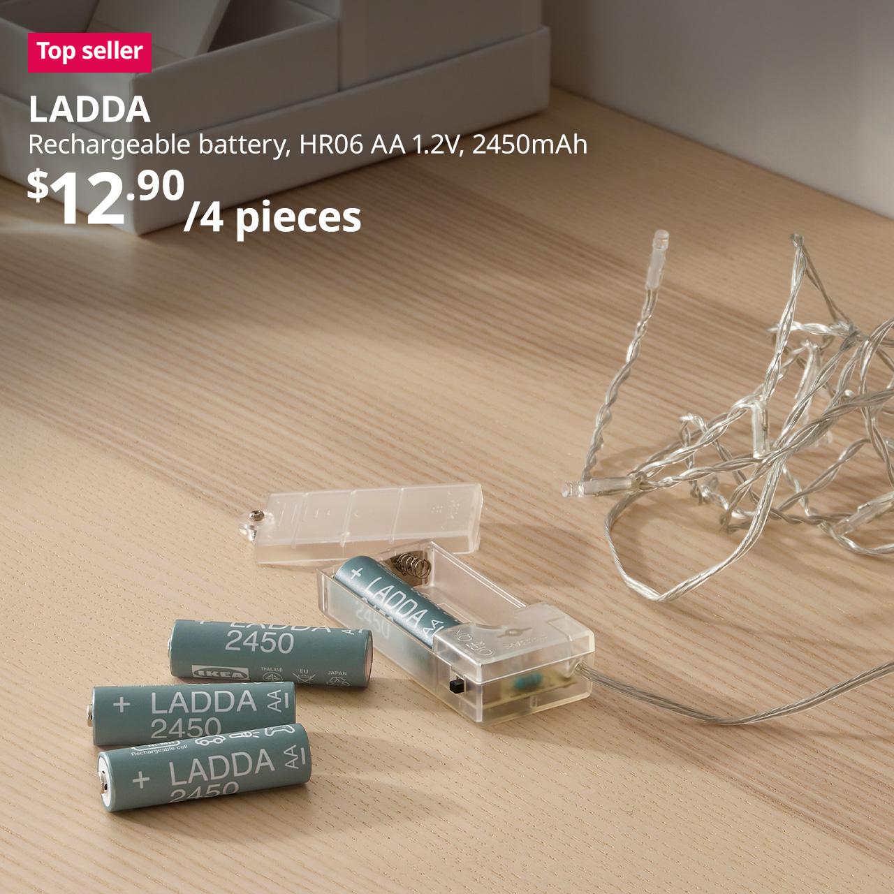 A mid shot of a LADDA battery placed on the desk, in the context of replacing the fairy lights' battery. A reddish-pink tag with white text that reads "Top seller," followed by a black text overlay image that reads "LADDA, Rechargeable battery, HR06 AA 1.2V, 2450mAh, $12.90/4 pieces".