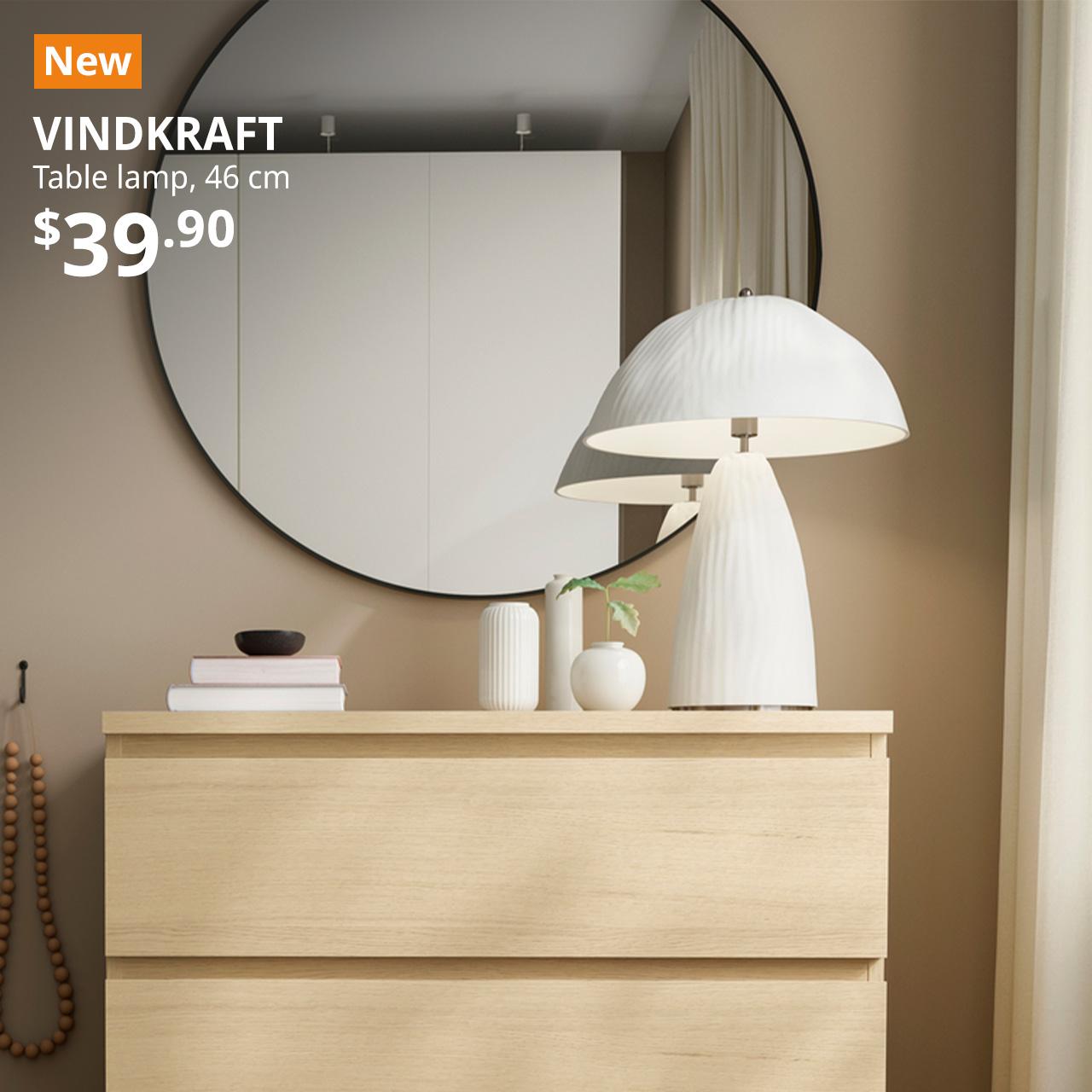 A mid shot of a white moulded paper pulp VINDKRAFT table lamp on a white stained oak MALM chest of 4 drawers at the corner of the bedroom setting. On the top left corner, a orange tag with white text that reads "New", followed by white text overlay image that reads "VINDKRAFT, Table lamp, 46 cm, 