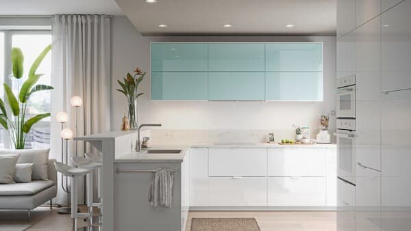 A minimalist kitchen with high-gloss white and turquoise doors, a cutting board with fruit, a blender with fruit.