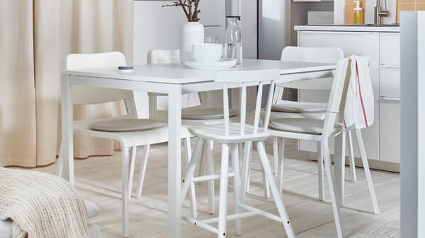 A minimalist white dining room with mismatched chairs.