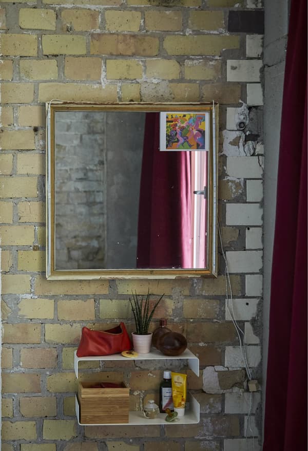 A mirror and shelves on a brick wall.