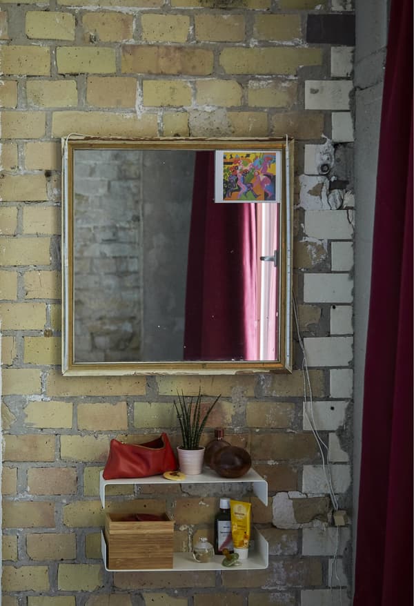 A mirror and shelves on a brick wall.