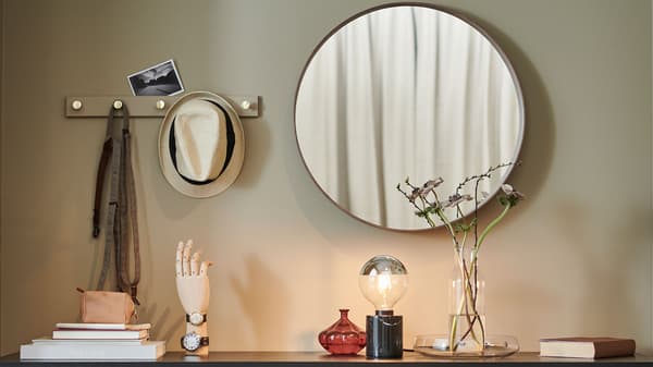 A mirror hanging above a chest of drawers.