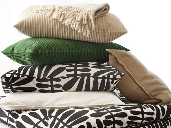 A mixture of bed textiles stacked on top of each other with brown, black and white colors in front of a white background.