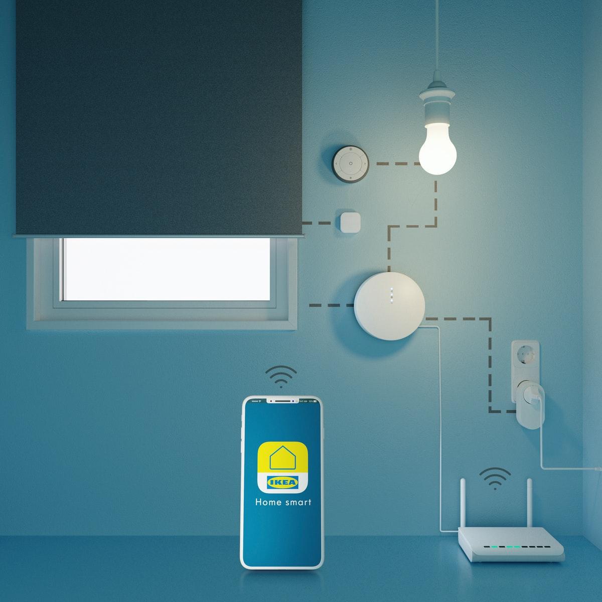 A mobile phone and a wireless router stand in front of a wall with a window and pieces of electronic and electric equipment.