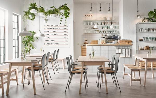 A modern beige, black and white café with white birch NORRÅKER tables and SVENBERTIL chairs in black and chrome.