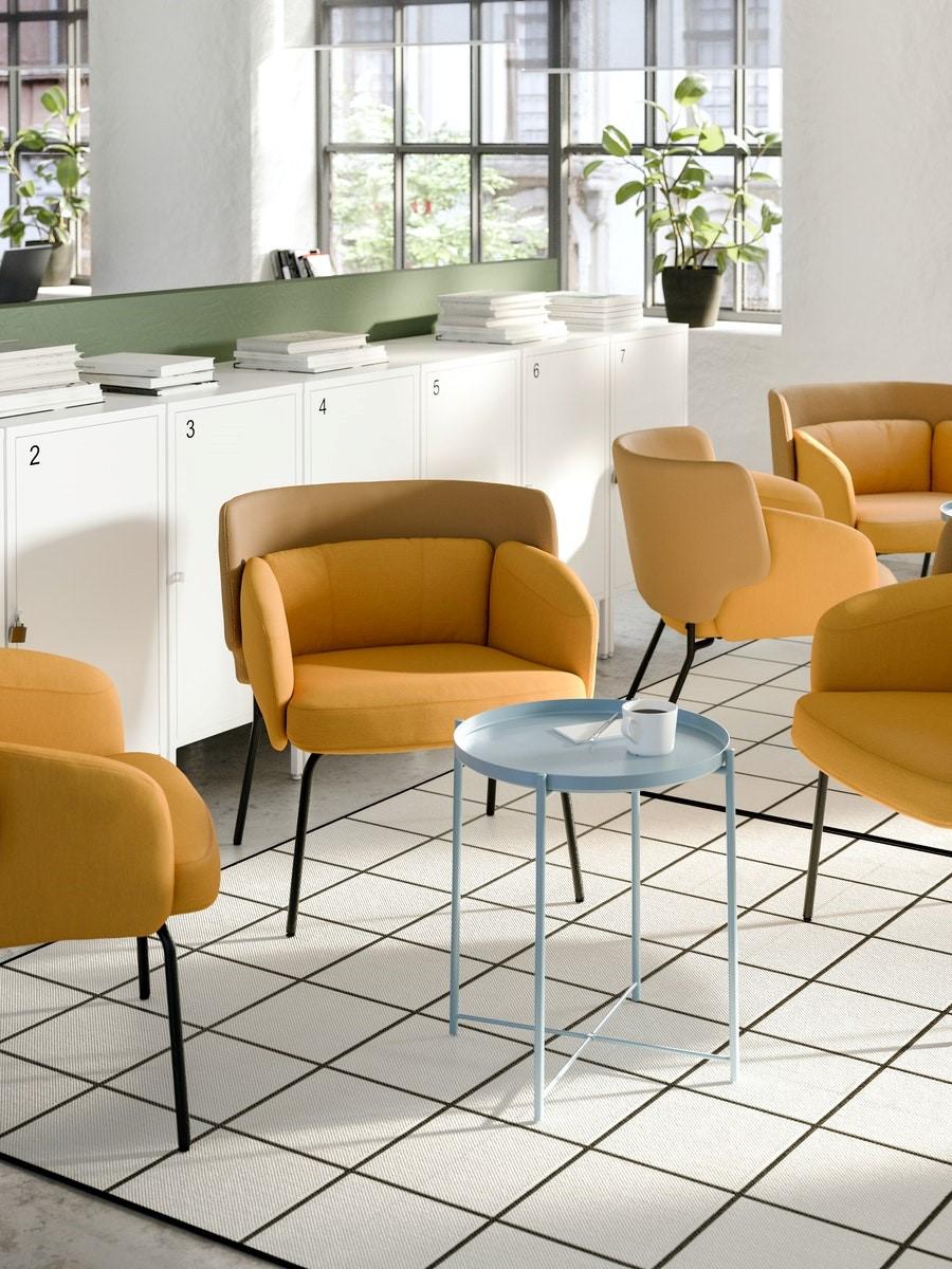 A modern business lobby with yellow chairs and blue side tables.