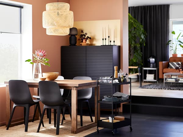 A MÖRBYLÅNGA table in brown-stained oak veneer and four ODGER chairs in anthracite are standing next to a NISSAFORS trolley.