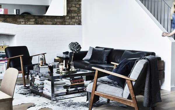 A monochrome living room with two IKEA armchairs and a black sofa.