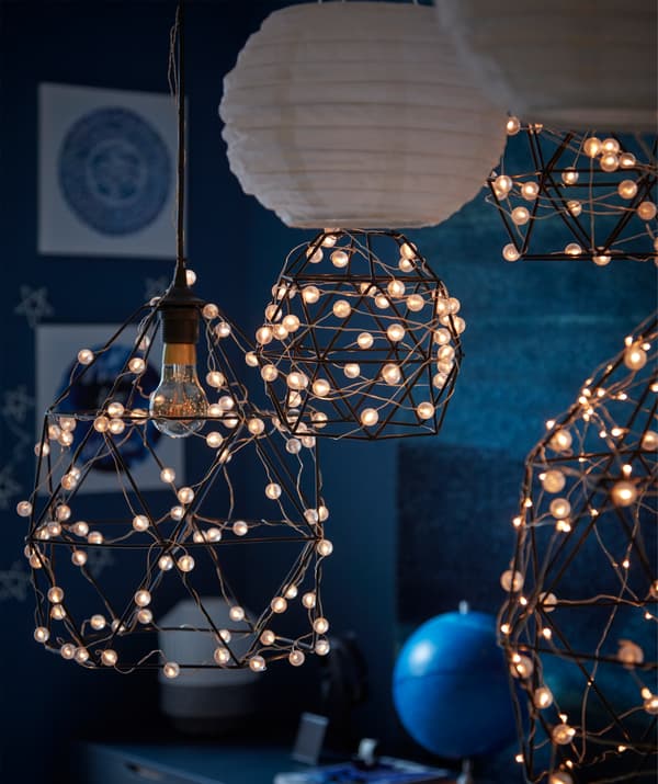 A moonlit, dark blue room with astronomy-themed lighting formed by BRUNSTA lamp shades wrapped in SNÖYRA string lights.