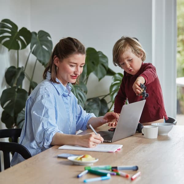 A mother designs her own BESTÅ storage system via the BESTÅ planner while her son is playing with toys.