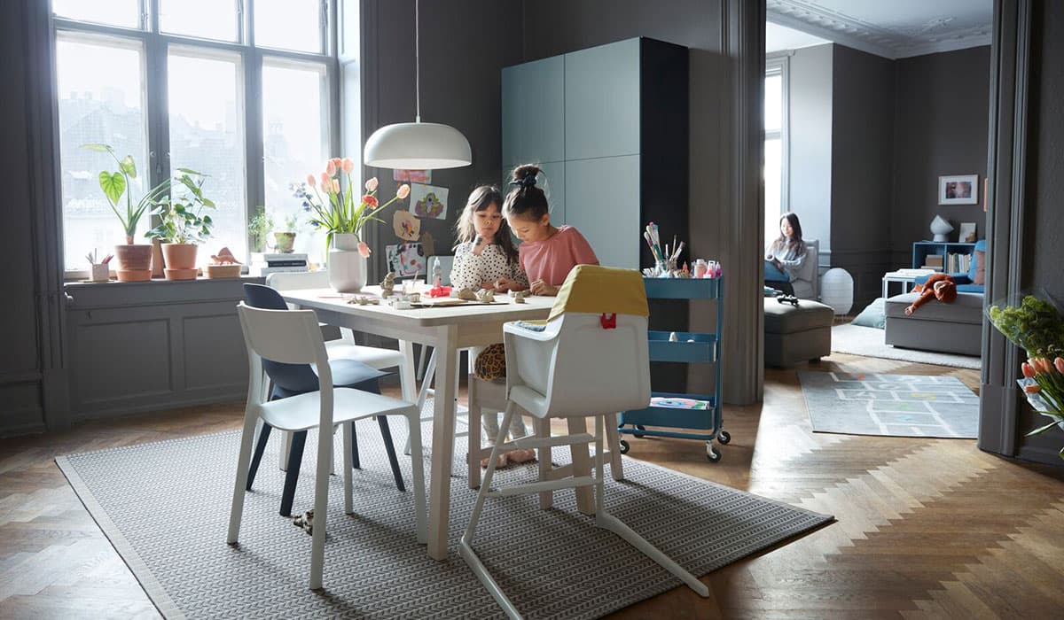 A mother sits at a dining table with her child in a large kitchen-dining room. 