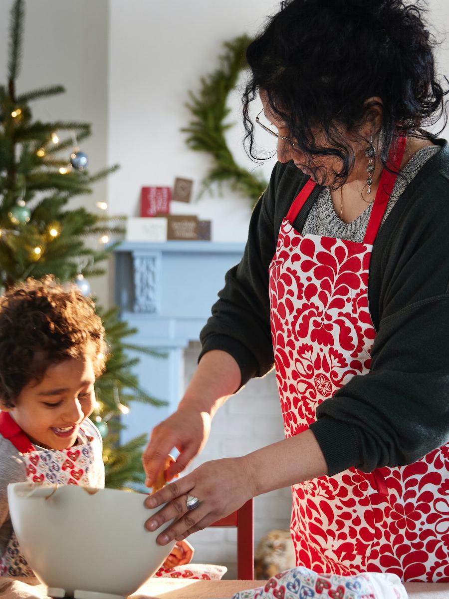 A mother wears the VINTERFINT 2022 apron and bakes with her son.