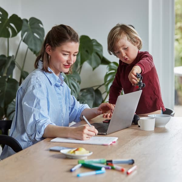 A mother working at home while her son plays beside her.