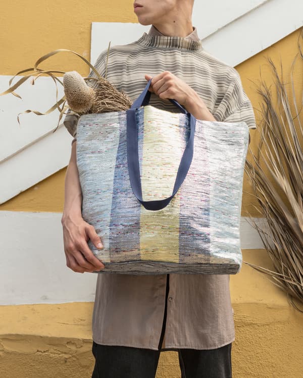A multicolored ÖVERALLT bag with handles in two different sizes, made from crisps packaging waste.