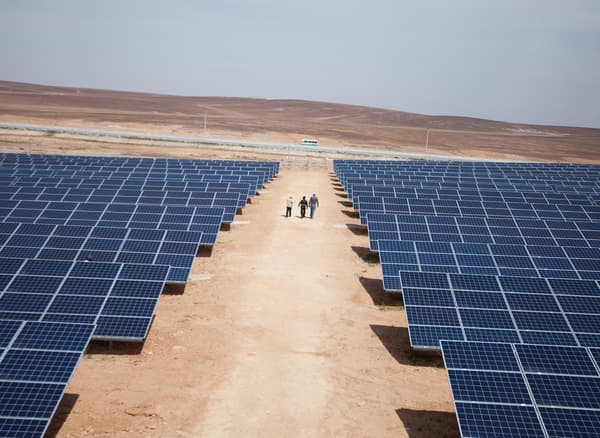 A multitude of solar panels mounted to the ground, situated in an arid plain.