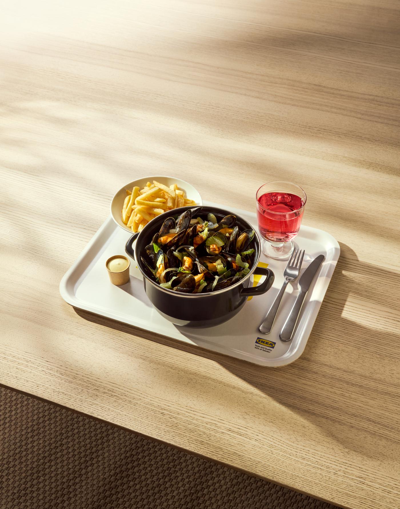 A mussel dish with fries and drink.