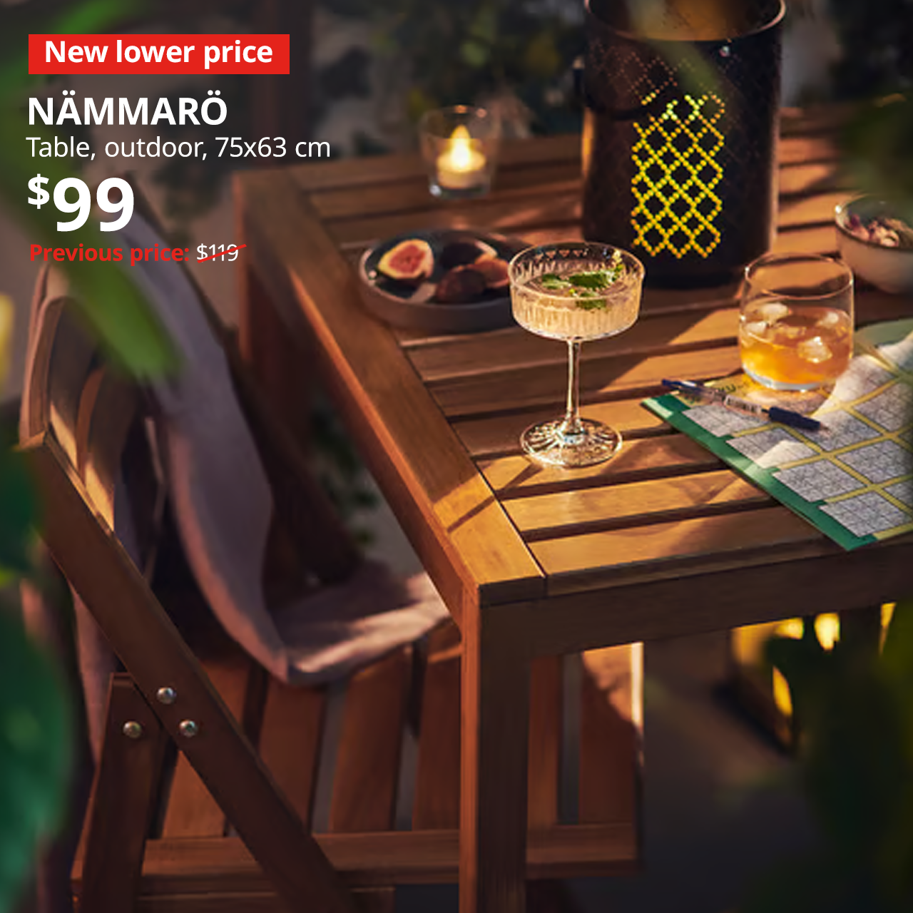 A NAMMARO table in an outdoor balcony space with candles, outdoor lamps and some food on the table. . A red "New lower price" label is on the top left of the image with white text that reads: NAMMARO, table, outdoor, 75x63 cm, Price at $99, Previous price, $119.