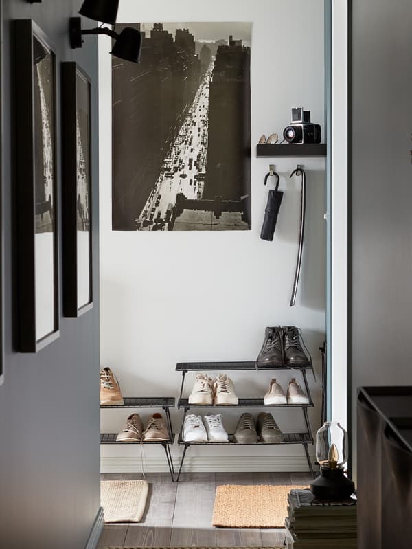A narrow hallway with pictures, including a cityscape, and an umbrella and a shoehorn hanging on the walls.