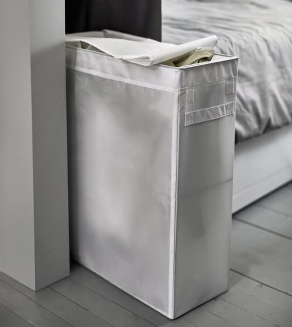 A narrow white laundry bag sits at the foot of the bed.