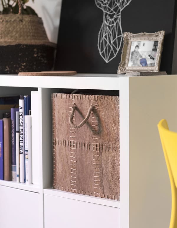 A natural fibre box fits perfectly on a white KALLAX shelf.