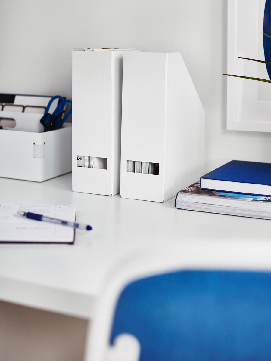 A neatly organized desk with white file holders, a pen, and notebooks