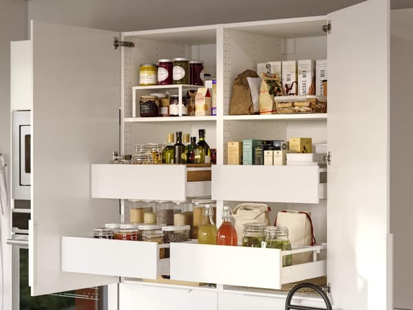 A neatly organized white kitchen pantry with open shelves and pull-out drawers holding jars, oils, dry goods, and condiments.
