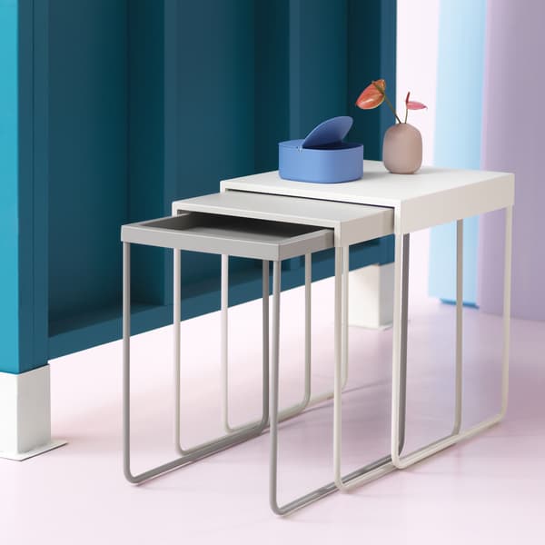 A nest of three tables in shades of grey and white.