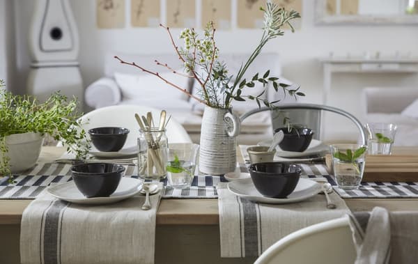 A neutral-coloured table setting with cotton napkins, simple place settings and a natural centrepiece.