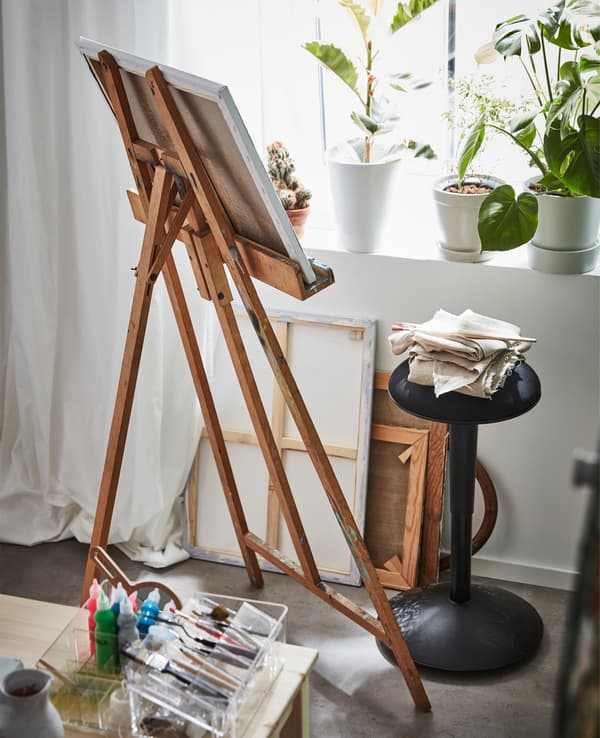 A NILSERIK standing support by a wooden easel in a student dorm room.