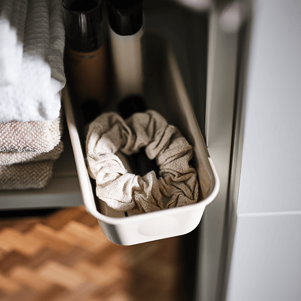 A NOJIG organizer filled with a hair scrunchy and hair products