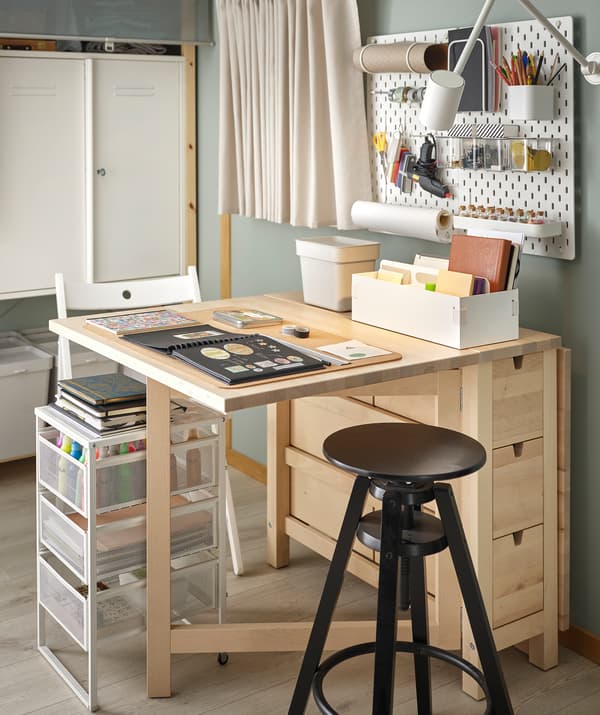 A NORDEN table arranged for scrapbooking, highly organized and accessories within reach on table, pegboard and in drawers.