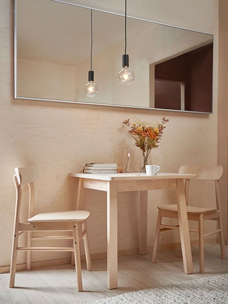 A NORRÅKER dining table with two RÖNNINGE chairs is standing under a HOVET mirror.