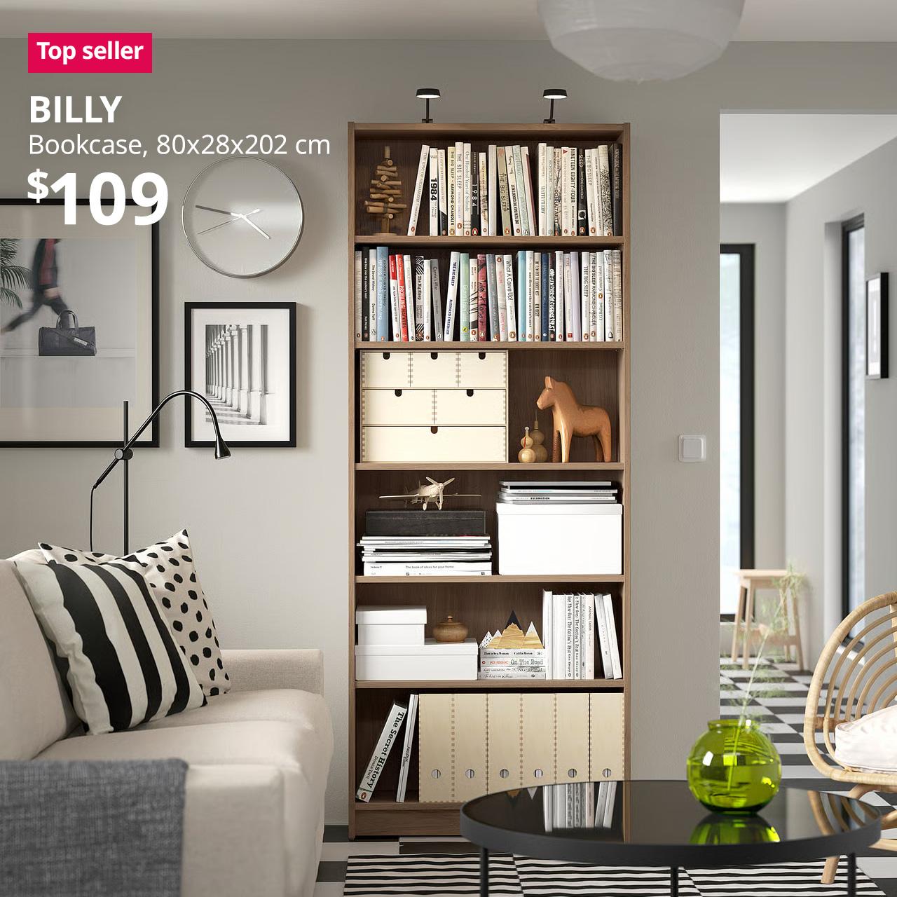 A oak effect BILLY bookcase is being to display books and decorative items in a living room setting. A reddish pink "Top seller"  tag is displayed on the top left corner of the image, followed by a white text overlay image that reads, "BILLY, Bookcase, 80x28x202 cm, $109"