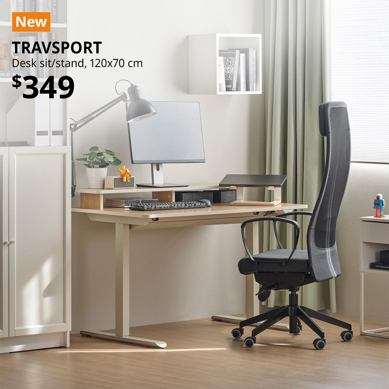 A oak effect/bneige TRAVSPORT sit/stand desk set-up in the corner of a living room setting next to a BILLY bookcase. In the top left corner, an orange tag with white text that reads, "New", followed by a white text overlay image that reads, "TRAVSPORT, Desk sit/stand, 120x70 cm, $349".